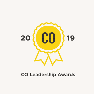 Image shows a yellow rosette on a cream background. The CO Leadership Awards champion fashion businesses that are pushing the boundaries of creativity, combining great products and services with business practices that change lives.