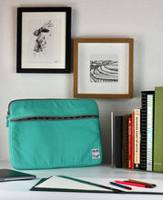 Load image into Gallery viewer, A teal 15 inch MacBook sleeve sits on a desk with pencils and a sketch pad ready to keep the 15 inch MacBook Laptop protected.
